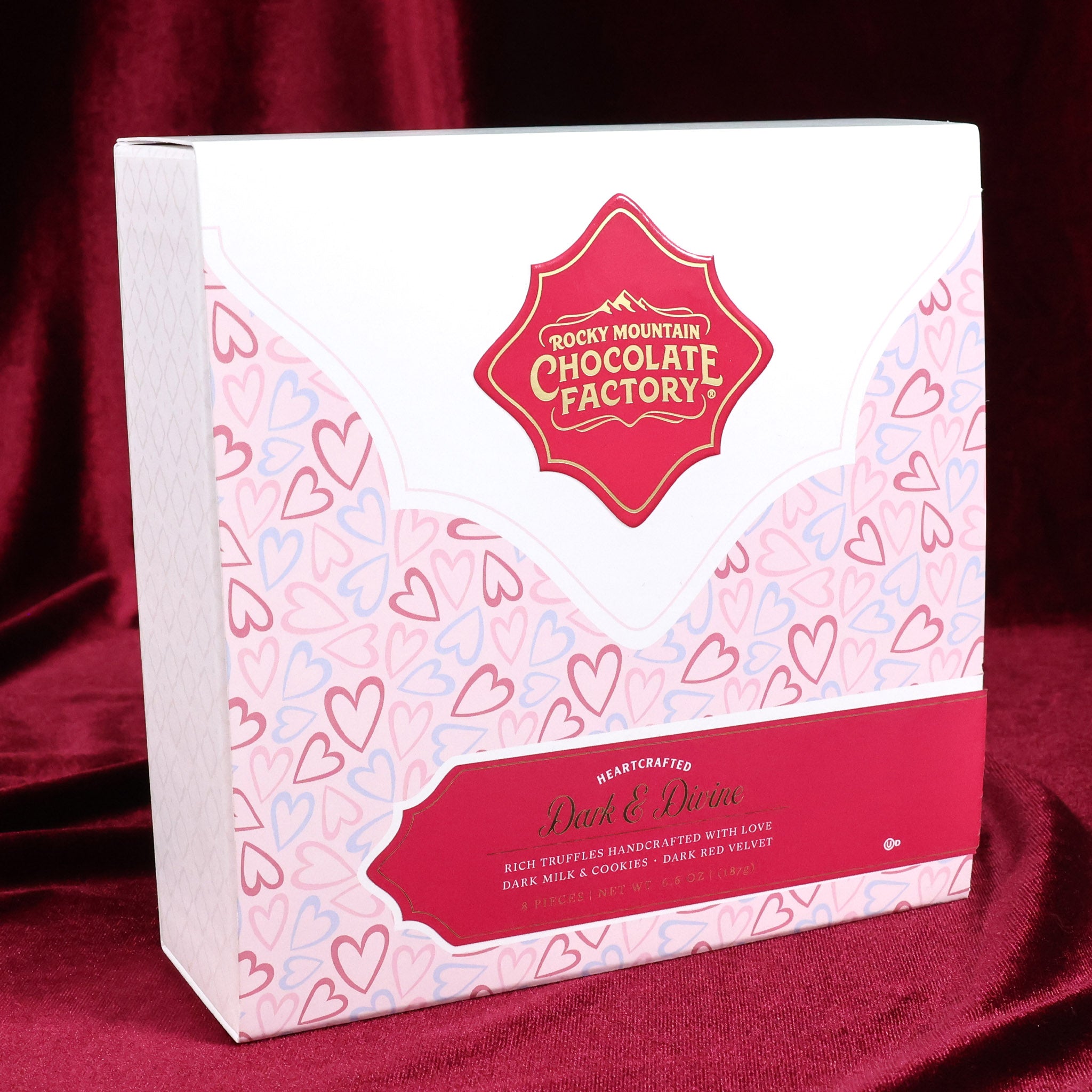 Chocolate packaging with heart patterns and Rocky Mountain Chocolate Factory logo on a red fabric background